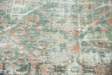 Faded teal, blush, and ivory tones on the distressed pile of a geometric Mahal carpet.