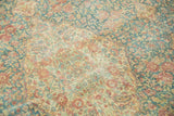 Distressed vintage Kerman carpet with faded millefleur design in sky blue, terracotta, and antique ivory.