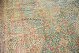 Distressed Kerman carpet's soft blue, rose, and ivory millefleur design with textured wear.