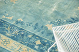 Distressed antique Peking rug, with a sky blue floral field and cobalt border.