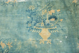 Storied antique distressed Peking carpet featuring a floral vase in powder blue and pale gold.