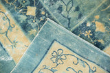 Distressed blue field and pale gold floral border on a folded antique Peking carpet.