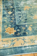 Distressed texture of an antique Peking carpet with faded blue, pale gold border, and floral motifs.