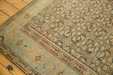 Distressed Malayer carpet with faded herati motif and a light blue geometric border.