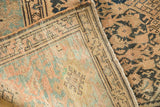 Distressed vintage Malayer rug corner, highlighting worn pile, secured edge, and woven foundation.
