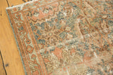 Distressed Malayer rug detail showcasing worn floral vinery in teal, terra cotta, and ivory.