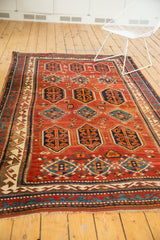 Close-up of vintage Kazak rug's madder root red field, mallard green blue border, and fringe.