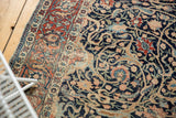 Antique Tabriz rug's intricate navy and terracotta field, with ornate floral designs and foundation wear.
