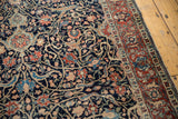 Intricate dark navy field of an antique Tabriz rug with floral palmettes and red border.