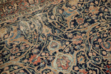 Antique Tabriz rug featuring intricate navy arabesques, terracotta flowers, and visible foundation.