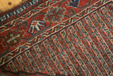 Worn vintage Qashqai rug detail with madder red zigzag and water motifs.