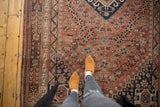 Vintage Qashqai rug displaying dark navy rams horn medallion on a dusty rust field.