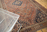 Vintage Qashqai carpet showcasing its navy diamond medallion, rams horn motif, and chestnut field patterns.