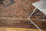 Vintage Qashqai carpet's rich field of stylized motifs and geometric borders in rust, navy, brown.