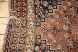 Qashqai carpet edge detail: tattered fringe, white cross-stitching, and chestnut geometric border.