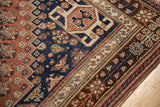 Geometric floral patterns in chestnut brown border and navy field of this Qashqai carpet.