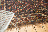 Detail of the antique Kamseh carpet's rich geometric border and tattered fringe.
