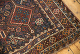 Antique Kamseh rug corner detail, showing geometric motifs in navy, chestnut, and dusty gold with light tatter.