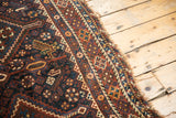 Antique Kamseh carpet detail: navy, chestnut patterns with stylized bird and lightly tattered edge.