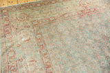 Distressed vintage Tabriz rug showing faded slate blue-green Herati and wine red border.