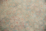 Textured pile detail of a distressed vintage Tabriz rug, with faded green, red, and ivory Herati motifs.