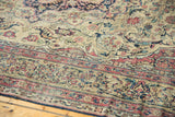 Intricate floral motifs and aged pile texture on an antique Persian Kermanshah rug.