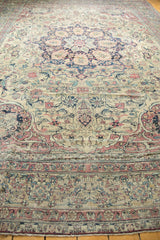 Antique Kermanshah carpet's intricate floral borders and field in soft ivory, cochineal red, and navy.
