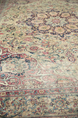 Curvilinear floral arrangements on Antique Kermanshah carpet, featuring cochineal red, navy, and ivory.