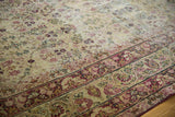 Antique Kerman carpet's cochineal red floral border and intricate ivory field, reflecting aged patina.