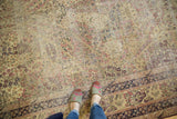Feet on antique Kerman carpet, highlighting ivory mil fleur tree-of-life and navy border.