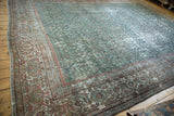 Distressed corner of a vintage Mahal carpet, featuring pale red and seafoam green vine border.