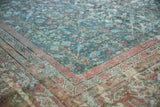 Distressed Mahal carpet corner features faded blue-green henna plant motifs and raspberry vine border.