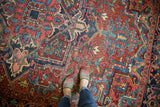 Low pile texture on a vintage Heriz rug, displaying geometric cherry red, navy, and aqua patterns.