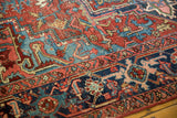 Vintage Heriz carpet detail: geometric patterns in cherry red, navy blue, aqua blue with low pile.