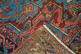 Folded corner of Vintage Heriz carpet, vivid aqua blue, red, ivory geometric patterns, fringe.