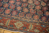 Navy blue ground with allover brick red boteh motifs meeting the geometric Heriz border.