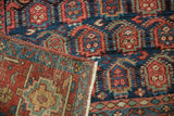 Folded vintage Heriz carpet revealing navy blue geometric pattern, wear, and woven foundation.
