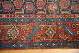 Vintage Heriz rug's geometric border in navy and brick red, showing faint foundation.