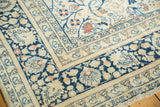 Angled detail of vintage Tabriz carpet corner, faded navy borders, ivory ground, scrolling tendrils.