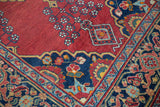 Cherry red field with vase floral motifs, navy blue scalloped contour, and low pile.