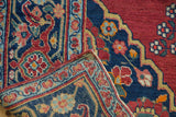 Folded corner of vintage Trans-Caucasian rug revealing hand-knotted foundation and secured red edge.