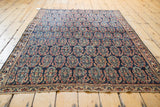 Intricate boteh pattern on the antique Afshar rug, featuring fine weave with navy, red, and gold.