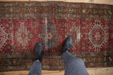 Central geometric medallion on a distressed vintage Karaja runner, in wine red and dark teal.