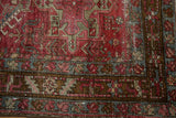 Distressed vintage Karaja rug close-up, low pile, wine red and dark teal geometric patterns.