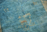 Distressed low pile of a vintage Peking rug with sky blue tones and visible knot heads.