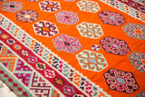 Vibrant tangerine orange Caucasian Kilim with scattered geometric guls and colorful patterned border.
