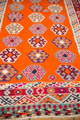 Geometric lower border of the Vintage Caucasian Kilim in varied colors and tangerine field with guls.