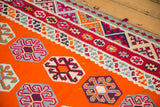 Close-up of unusual tangerine kilim field with geometric guls and funky patterned border.