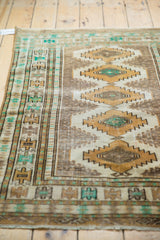 Distressed vintage Jaldar rug showing ivory, gold, and green serrated medallion detail.
