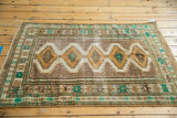 Distressed gold serrated medallions and intricate green border on a vintage Jaldar rug.